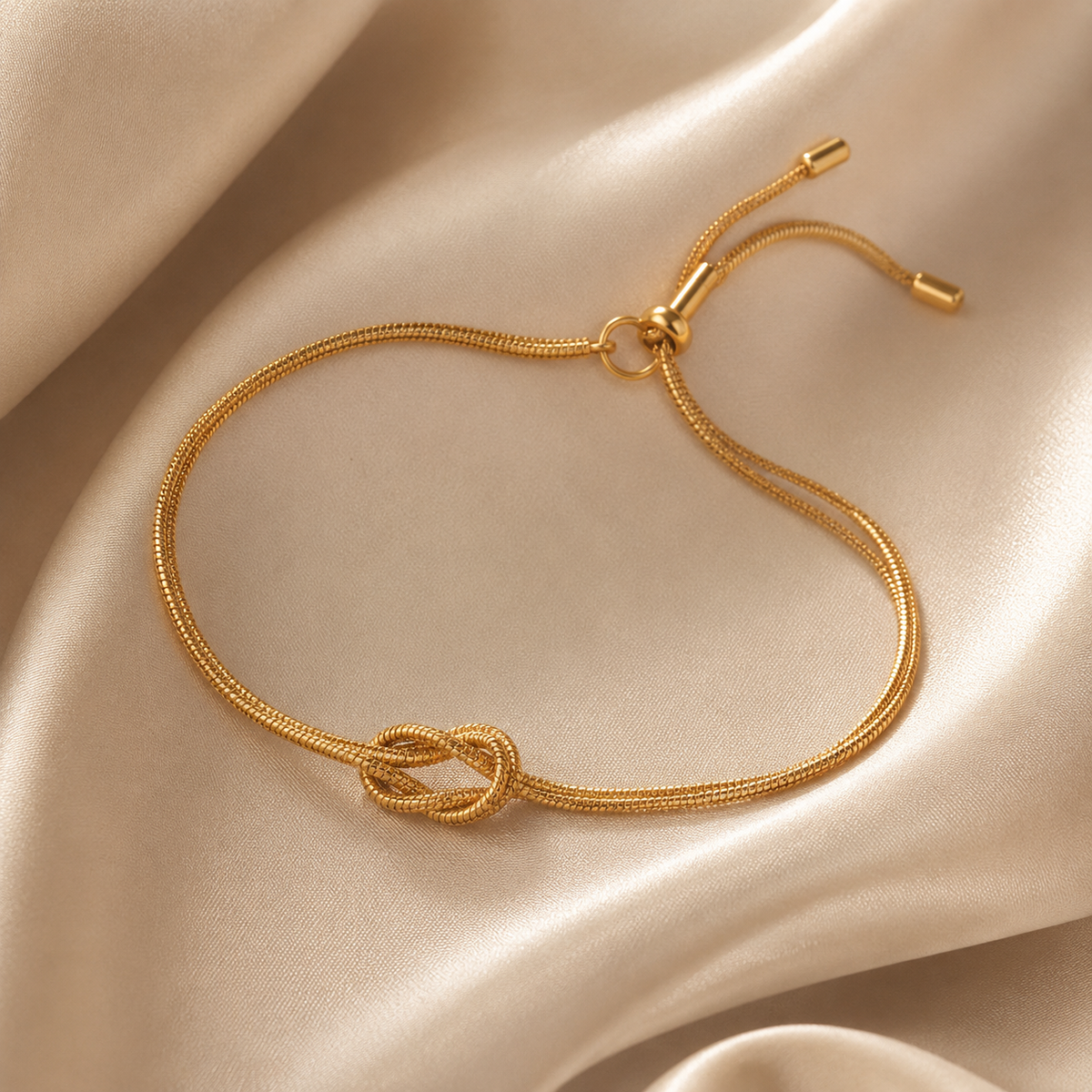 Gold bracelet with a knot design on a beige fabric background