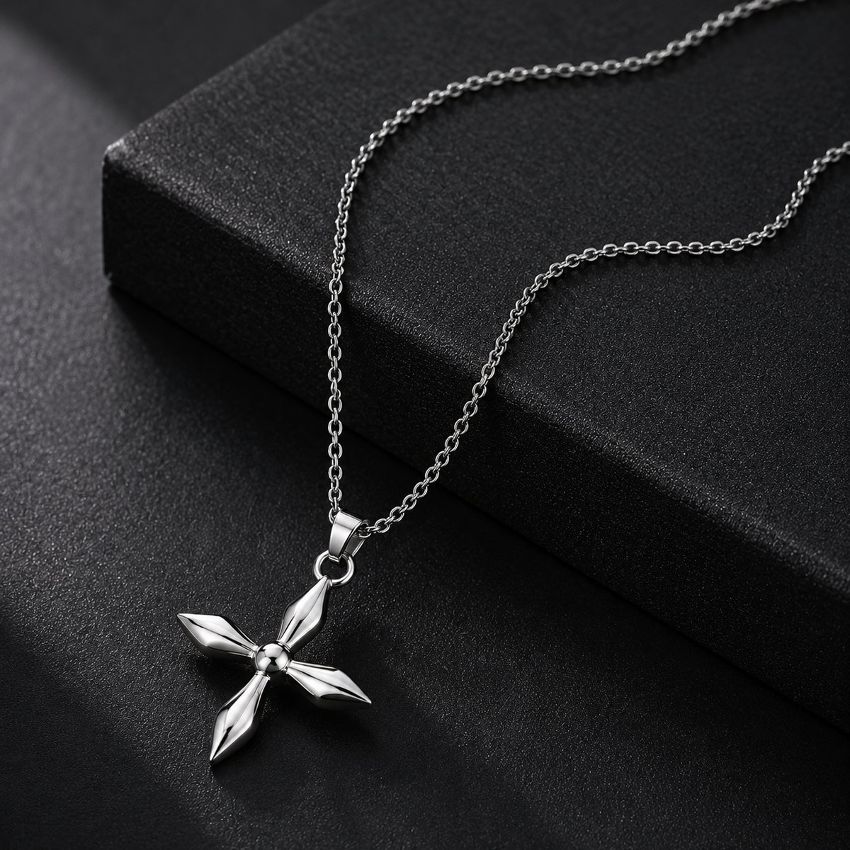 Silver cross pendant necklace on a black surface